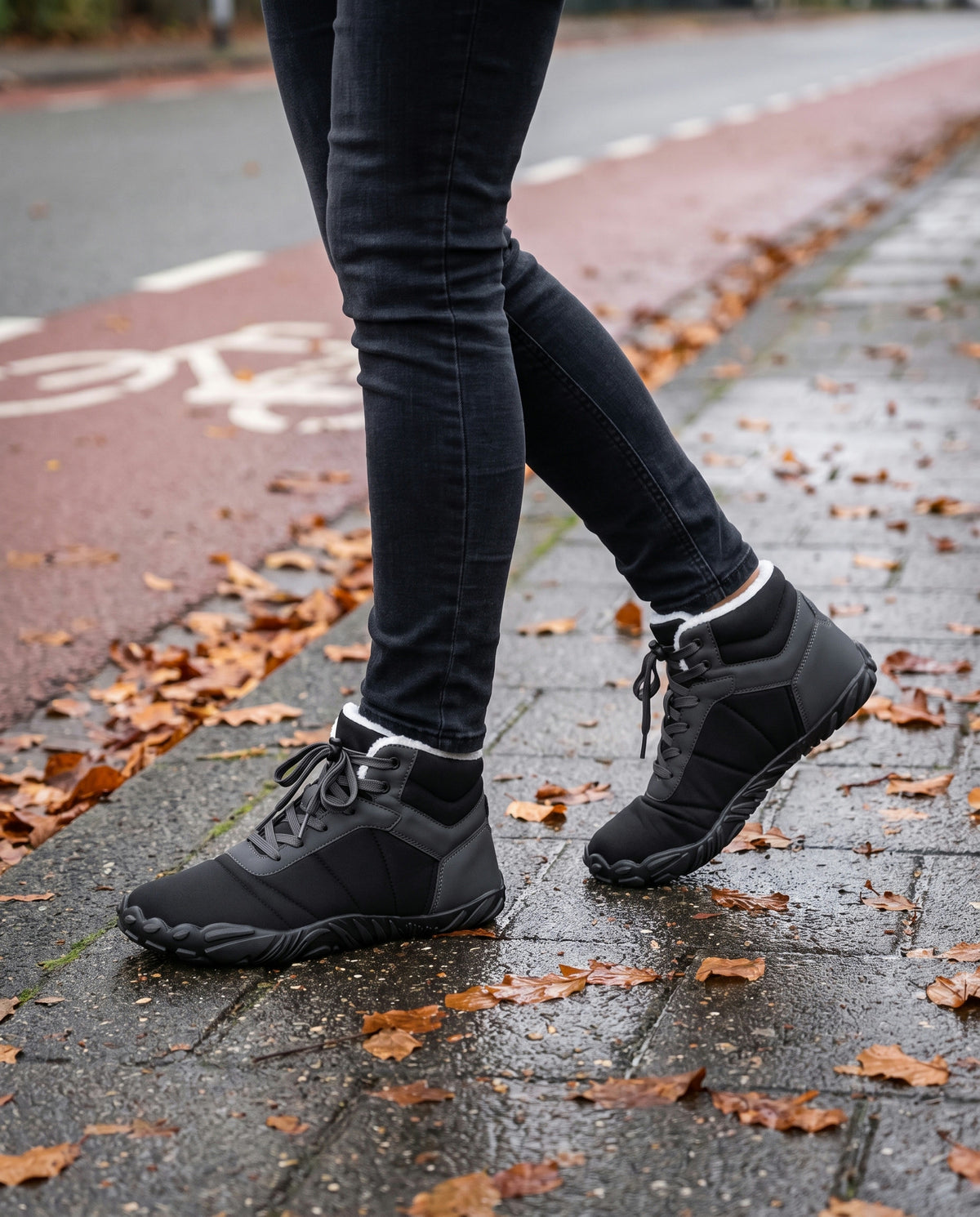 Bries winterboot gedragen buiten op een natte stoep langs een rood fietspad