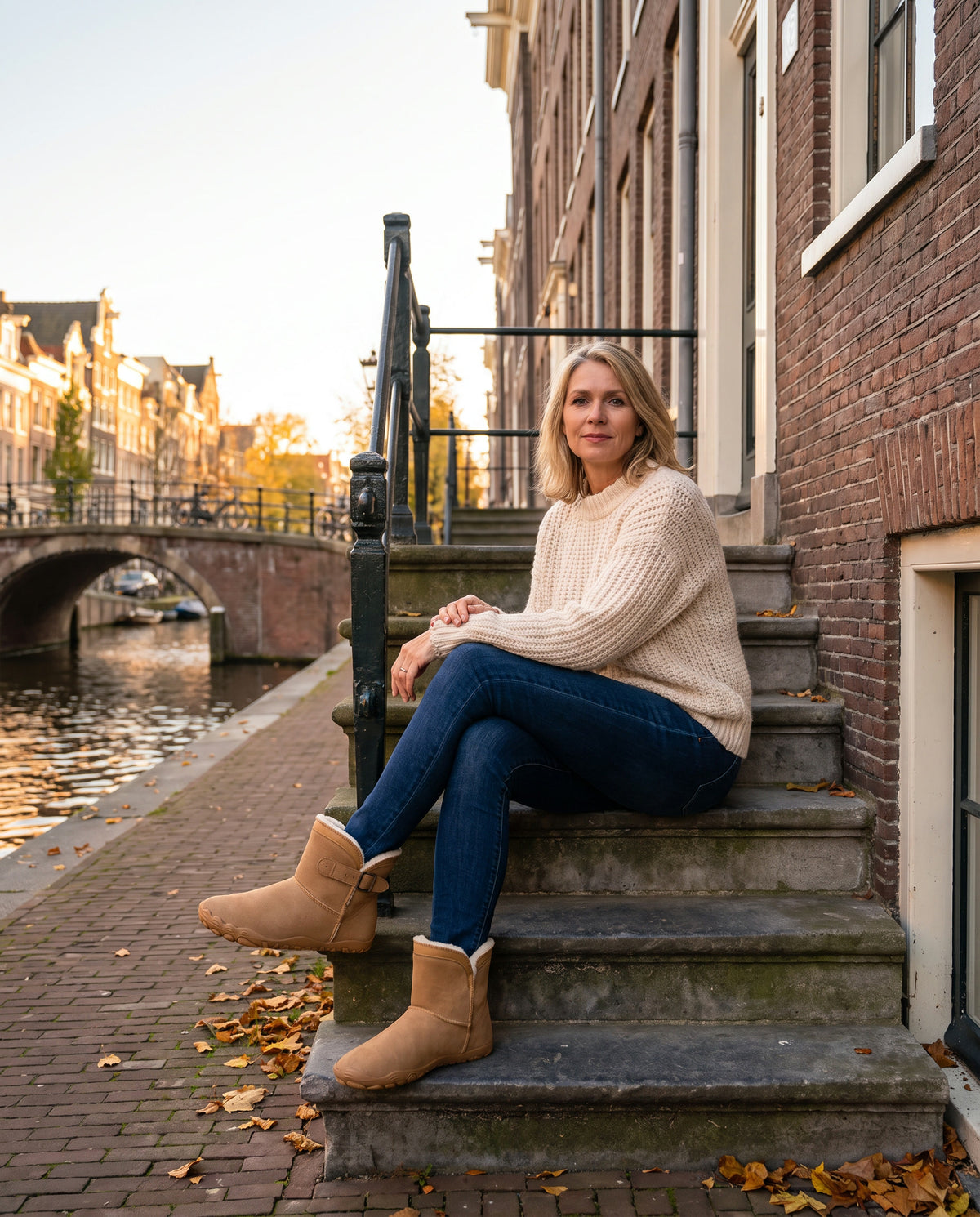 Vrouw op de stoep van een grachtenpand in de herfst, met bruine Snug Boots