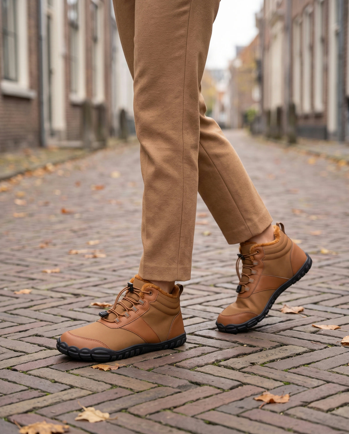 Kastanje winterboot gedragen buiten op een straat met visgraatklinkers en herfstbladeren