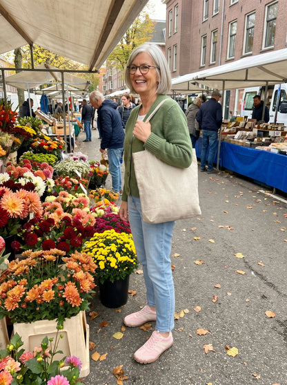 Vrouw van in de zestig op de markt met de roze Noor